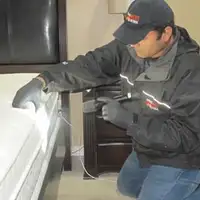 Bed bug inspection technician checking a mattress and bed frame for signs of infestation in Boise, ID
