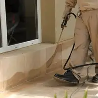General pest control technician spraying exterior perimeter around a home in Boise, ID