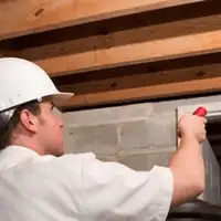 Termite inspection technician checking a basement wall and framing for termite activity in Boise, ID